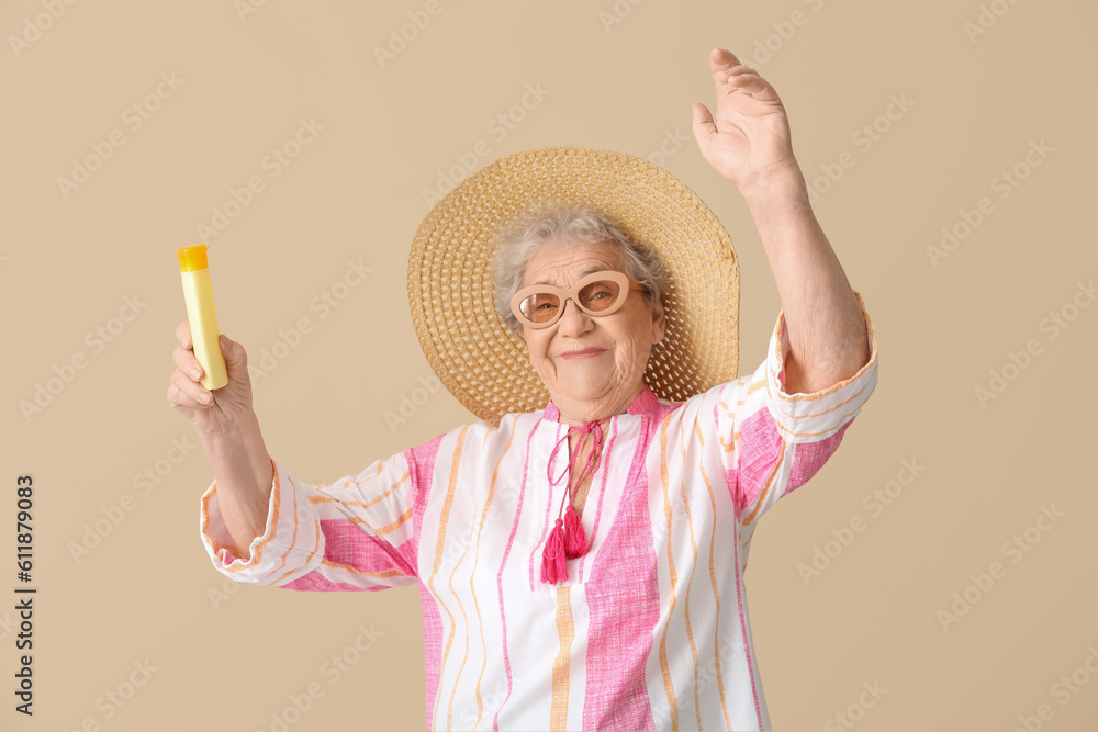 Senior woman with sunscreen cream on beige background