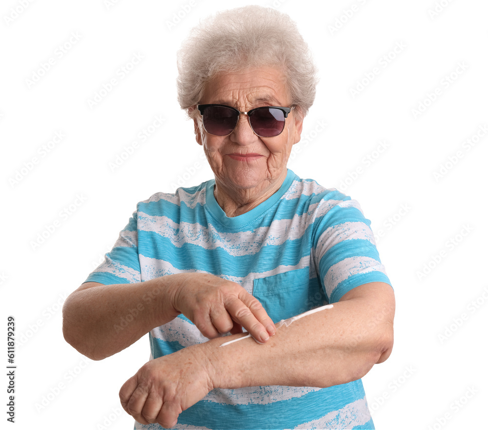 Senior woman applying sunscreen cream on white background