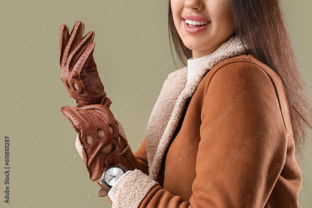 Stylish young woman in leather gloves on green background, closeup