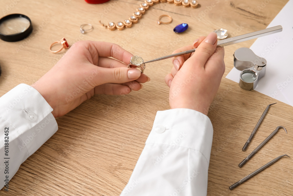 Female jeweler making ring on wooden table, closeup