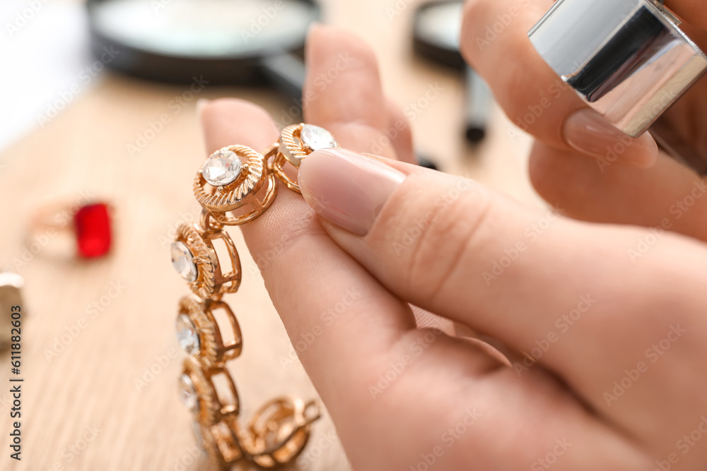 Female jeweler examining bracelet on wooden table, closeup