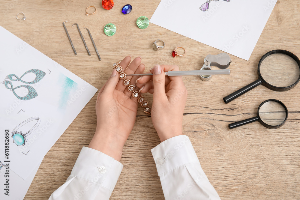 Female jeweler making bracelet on wooden table, top view