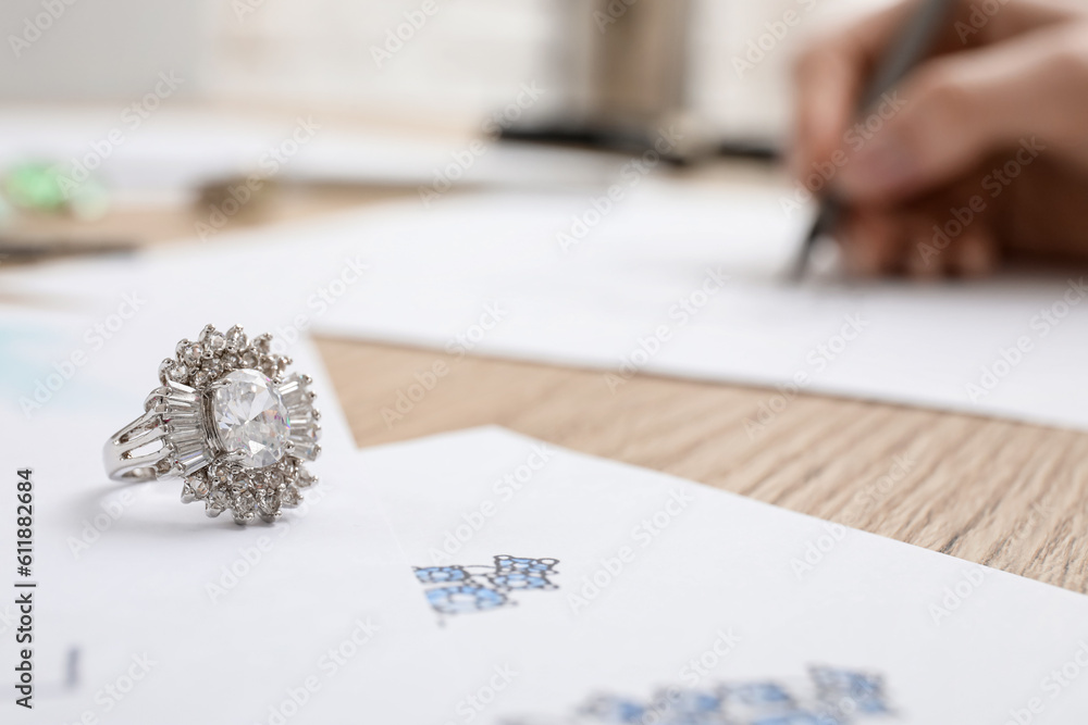 Ring with jewelers drawings on wooden table, closeup