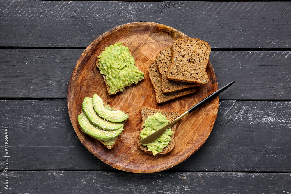 Plate of tasty avocado toasts on dark wooden background