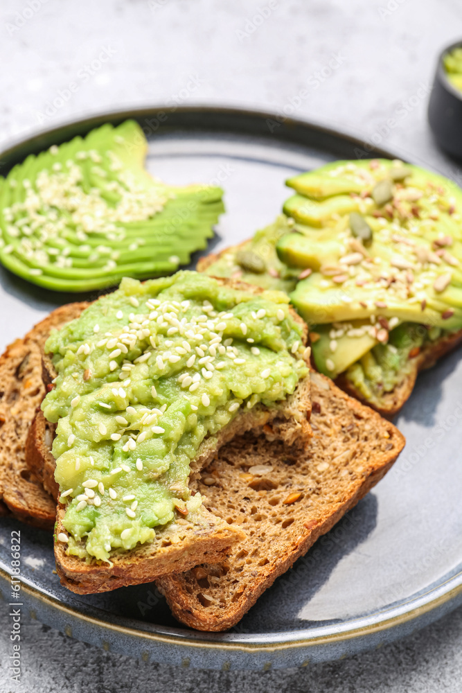 Plate of tasty avocado toasts on light background, closeup