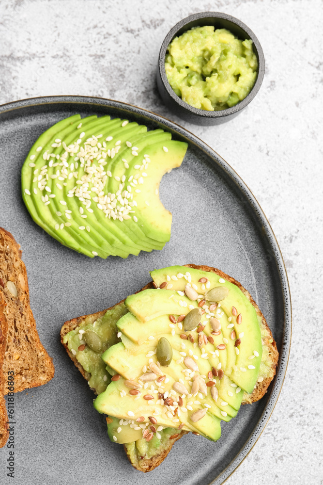 Plate of tasty avocado toast on light background, closeup