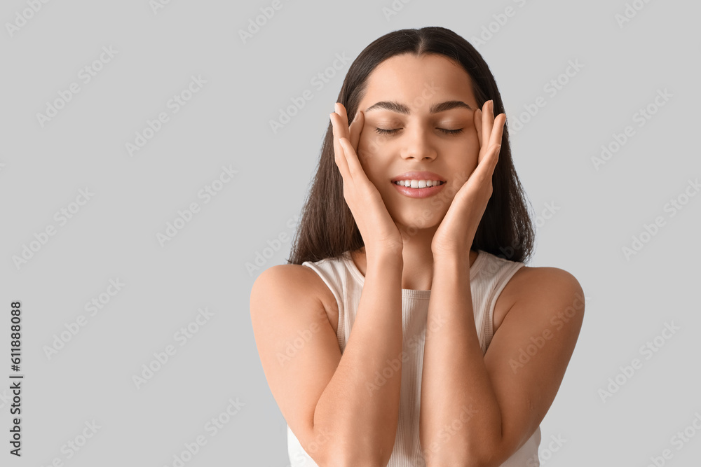 Young woman doing face building exercise on light background, closeup