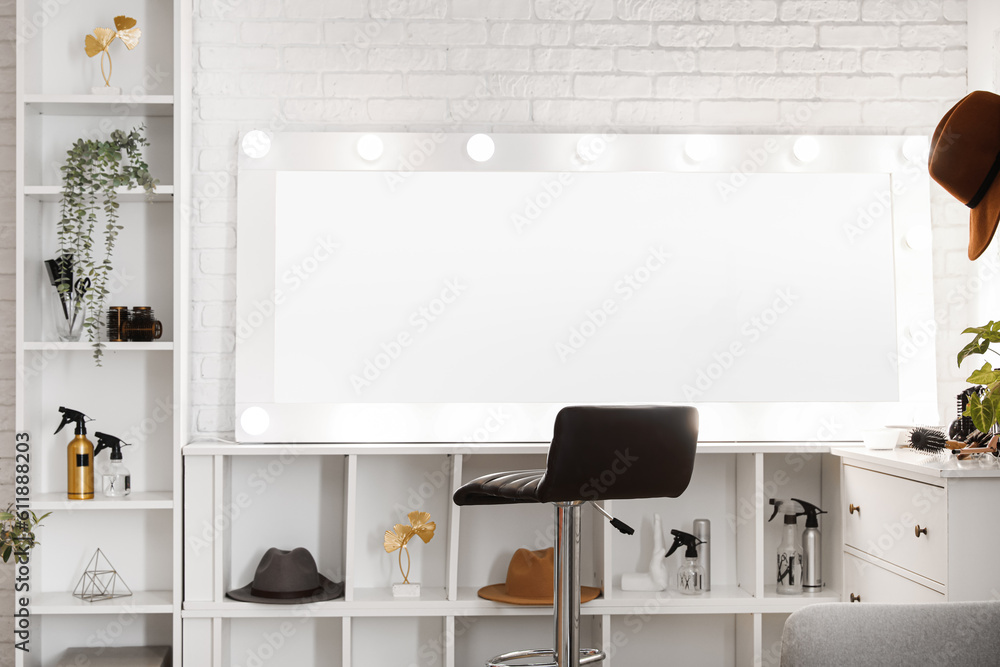 Modern mirror, shelves and chair near light brick wall in beauty salon