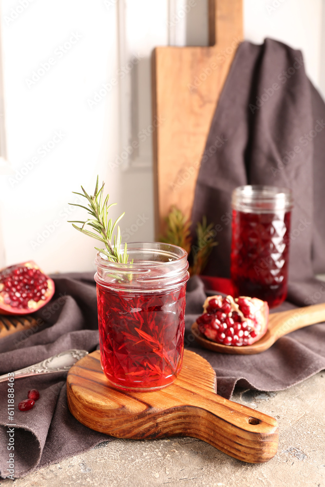 Spoon with fresh pomegranate and glasses of juice on grey table