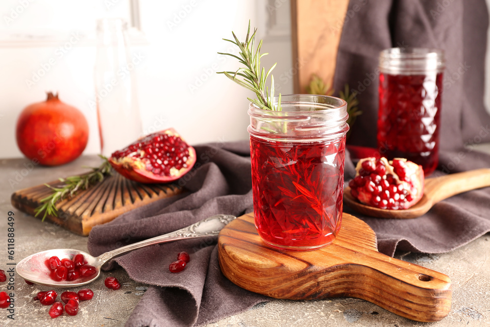 Spoon with fresh pomegranate and glasses of juice on grey table