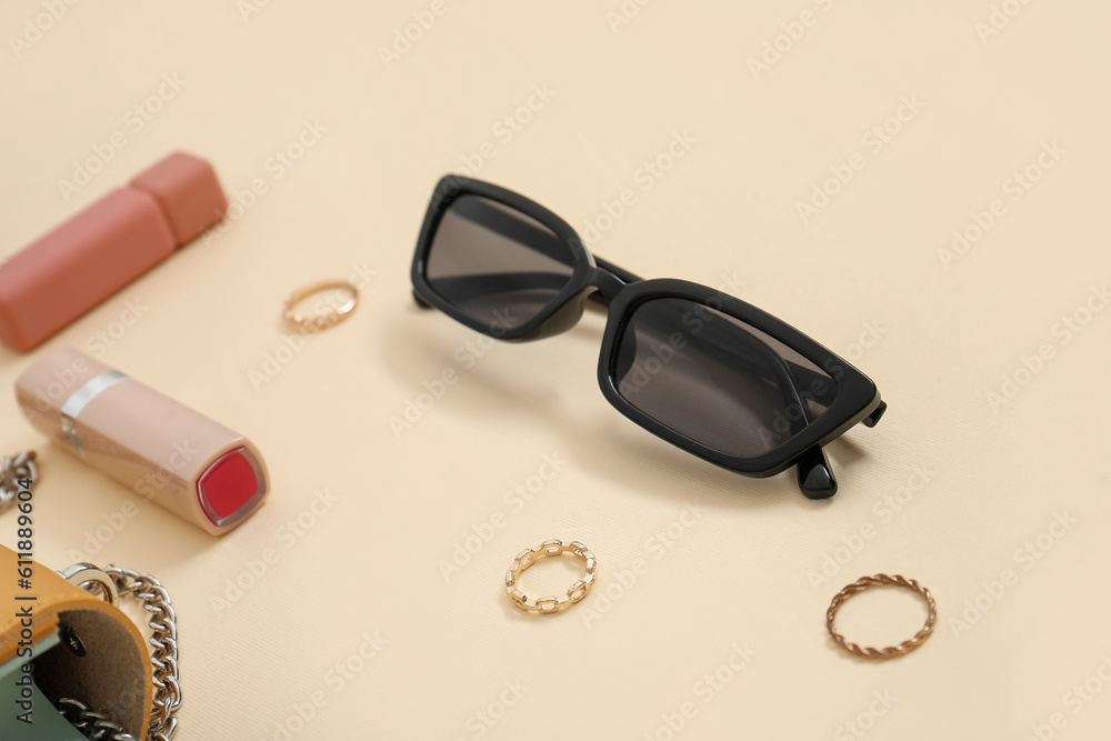 Sunglasses, gypsophila flowers, jewellery and lipsticks on yellow background, closeup