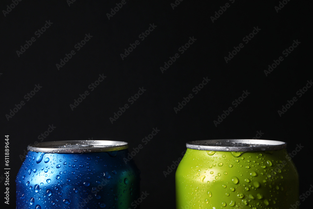 Cans of soda with water drops on dark background, closeup