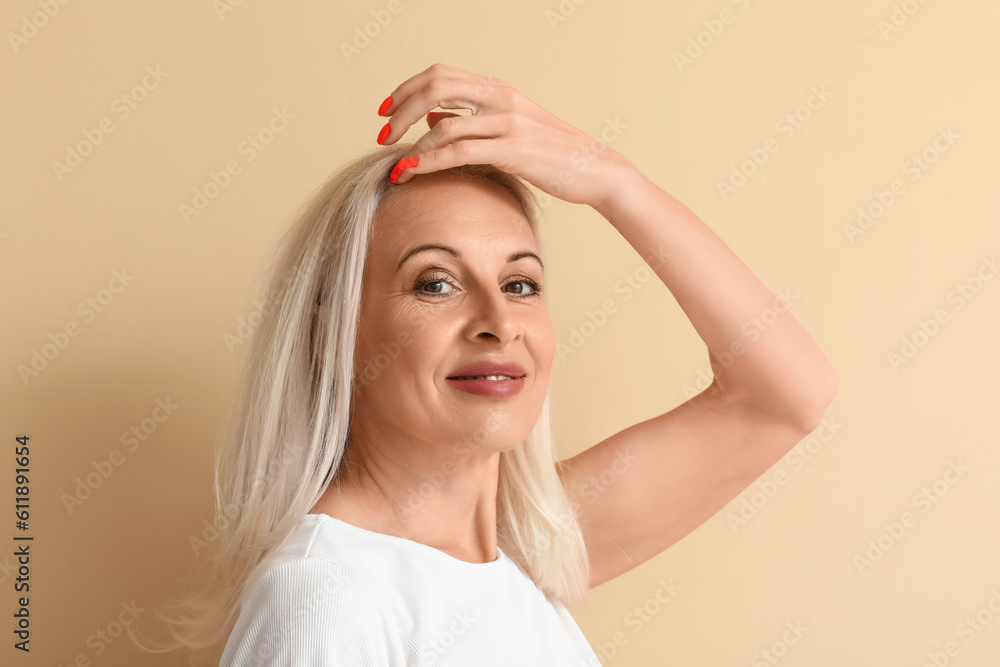 Mature blonde woman on beige background, closeup