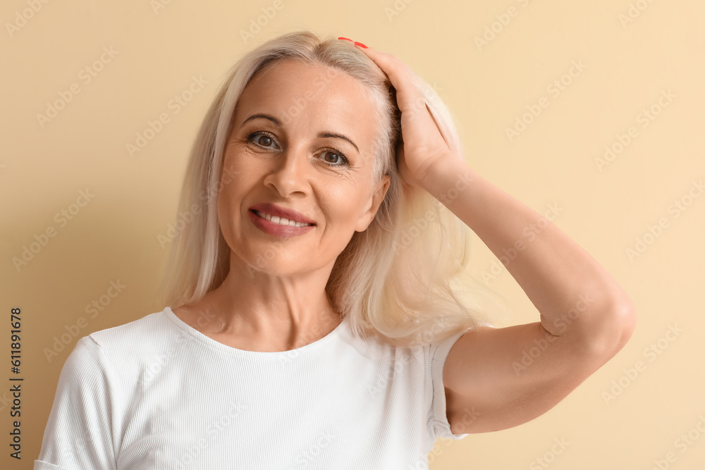 Mature blonde woman on beige background, closeup