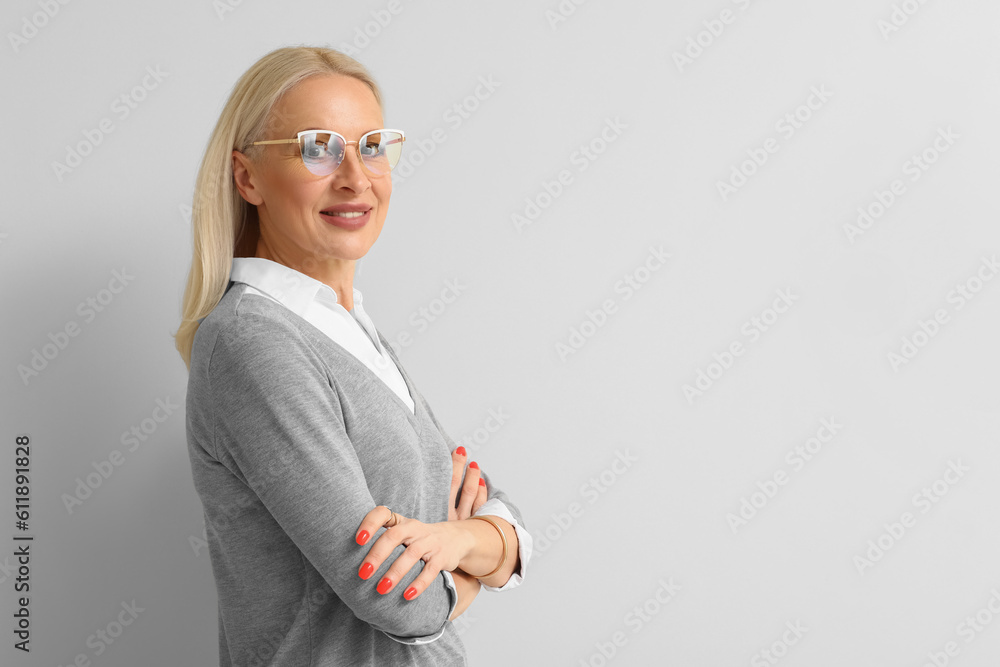 Mature blonde woman in eyeglasses on light background