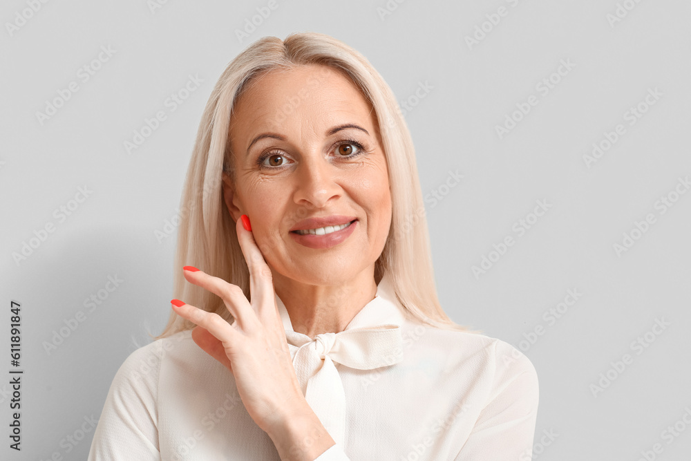 Mature blonde woman on light background, closeup