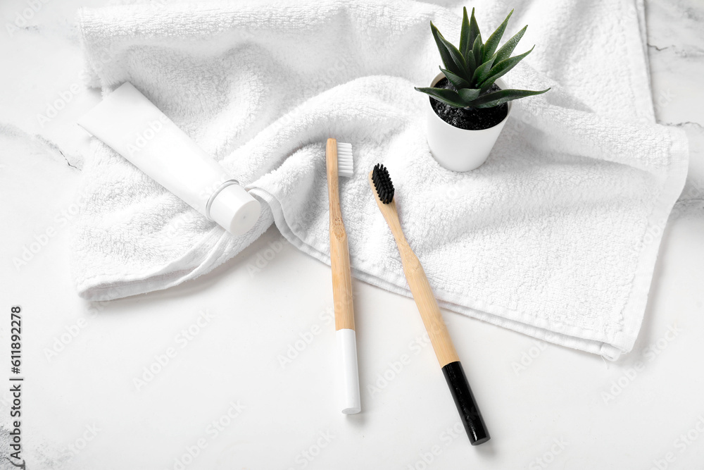 Bamboo toothbrushes with towel on white marble background