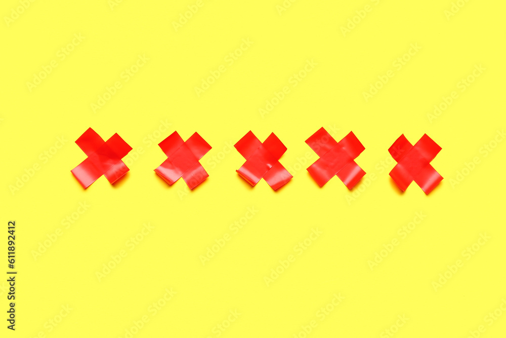 Red crosses made of adhesive tape on yellow background