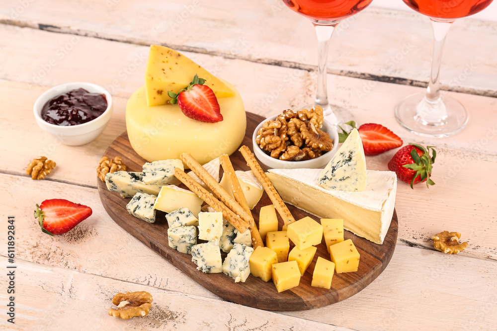 Board with pieces of tasty cheese on light wooden background