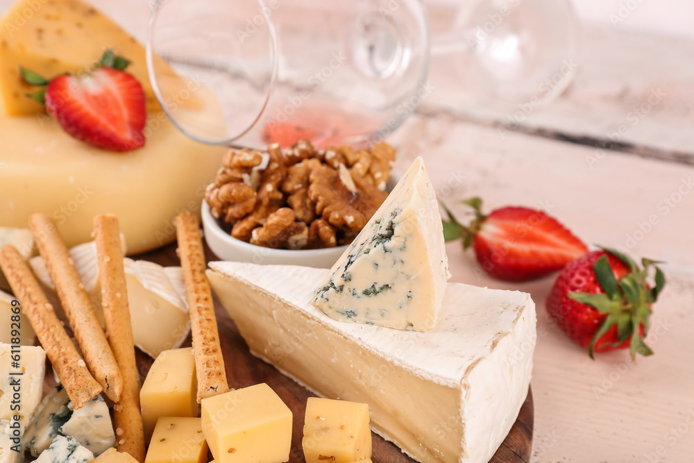 Board with different tasty cheese on light wooden background