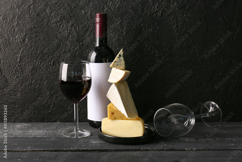 Different tasty cheese, glasses and bottle with wine on table