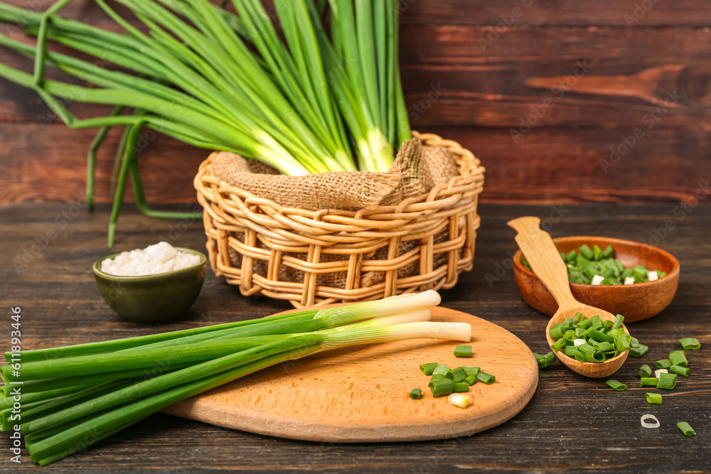 Board with fresh green onion on wooden background