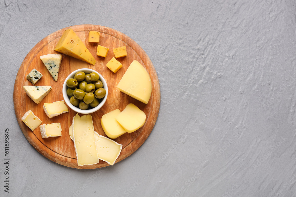 Wooden board with pieces of tasty cheese on grey background