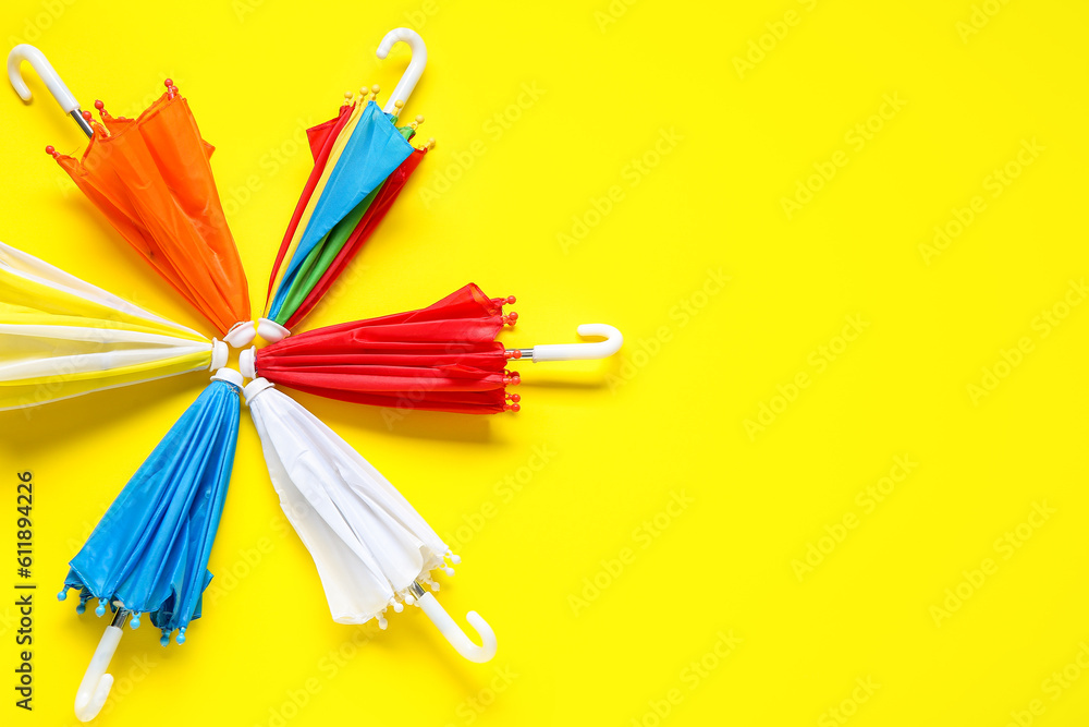 Composition with different umbrellas on yellow background