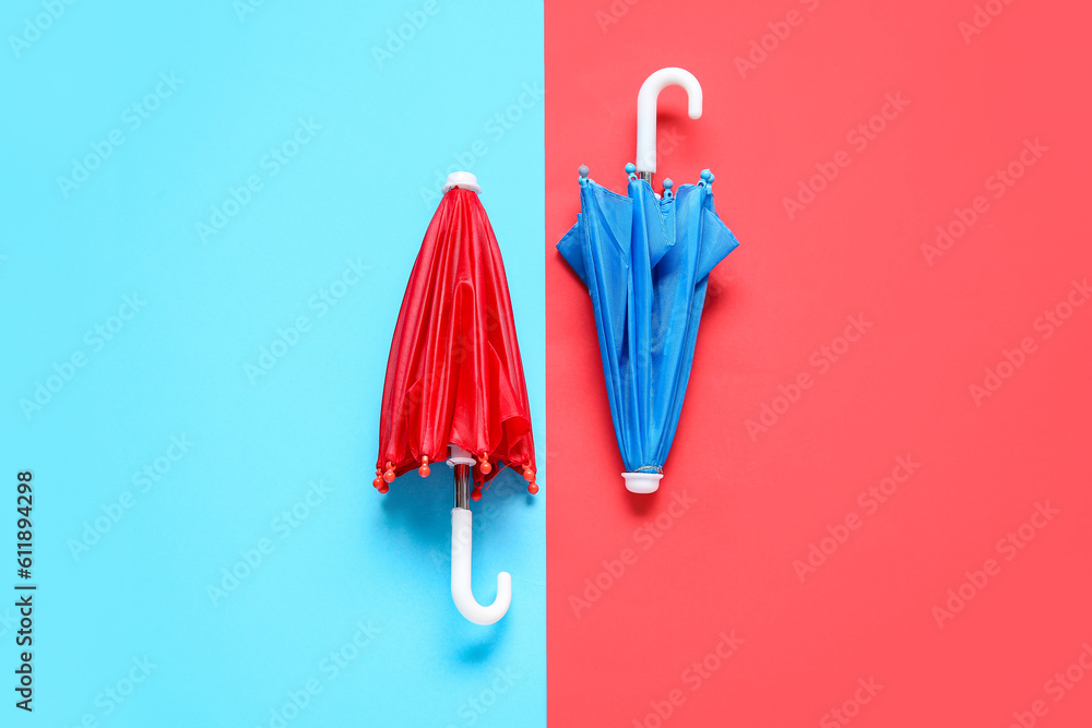 Red and blue mini umbrellas on color background