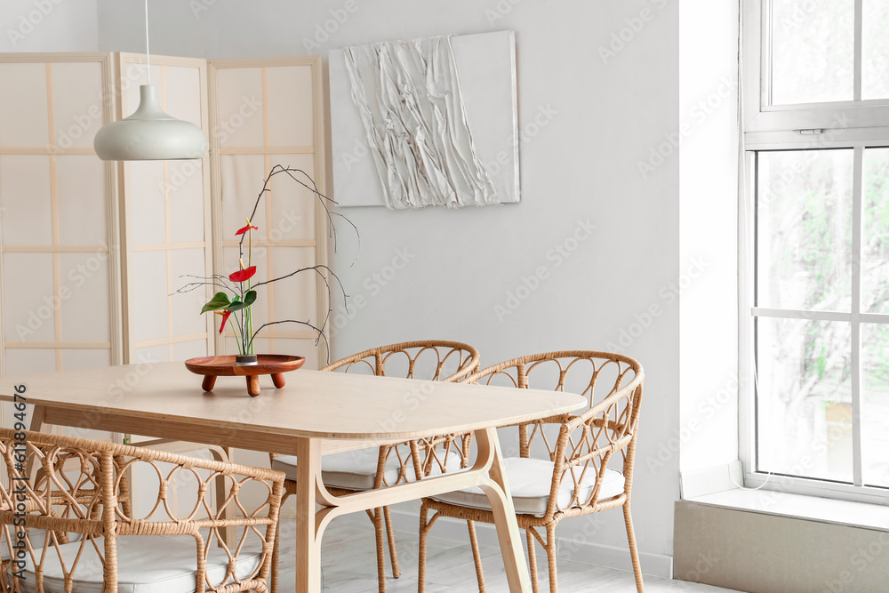 Dining table with beautiful ikebana in interior of room