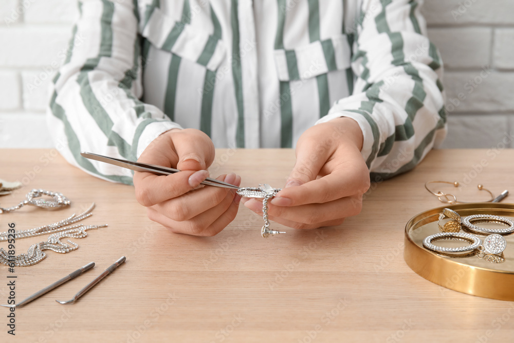 Woman cleaning beautiful jewelry at wooden table