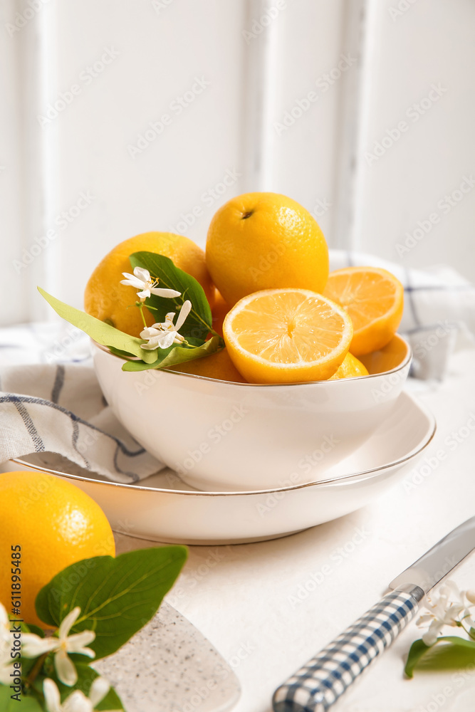 Bowl of lemons with blooming branches on white table