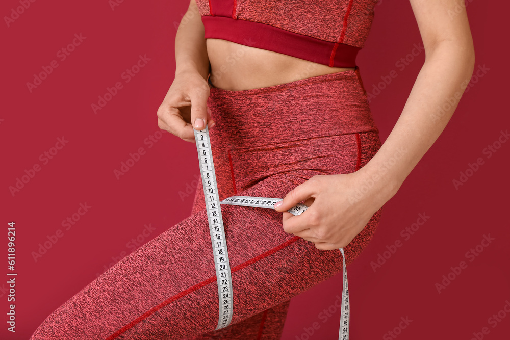 Young woman with measuring tape on burgundy background. Diet concept