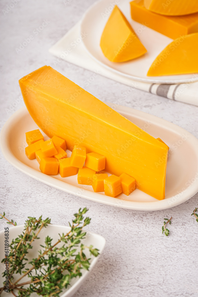 Plate with tasty cheddar cheese on light background