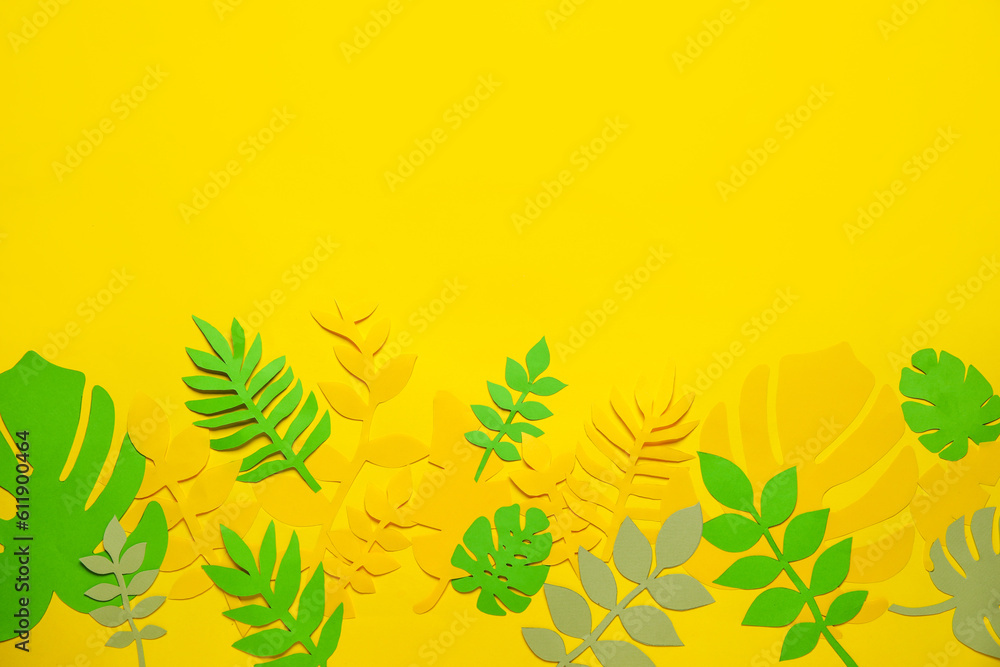 Different paper tropical leaves on yellow background