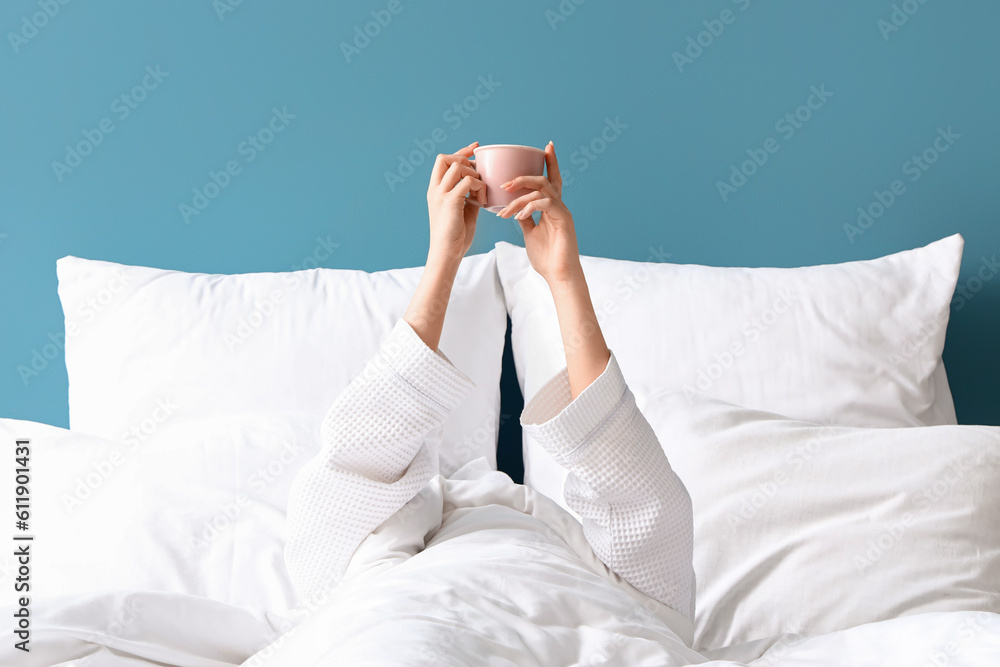 Morning of young woman with cup of coffee in bed