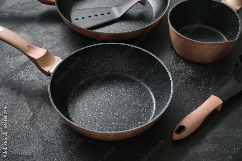 Cooking pot and frying pans on dark background, closeup