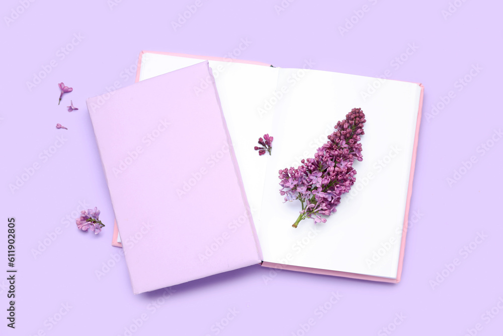 Lilac twig on open notebook on color background