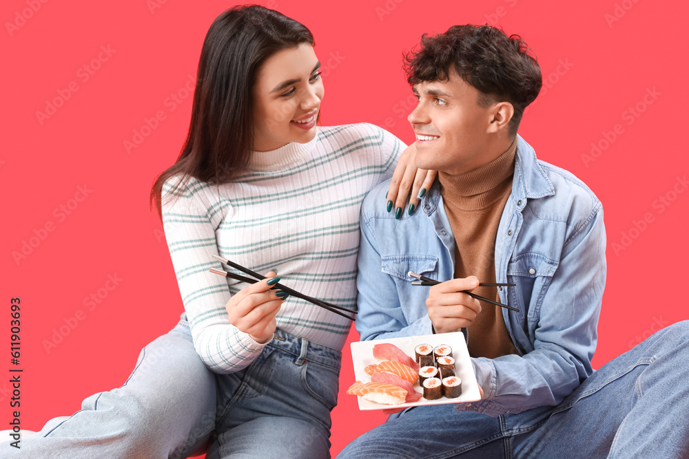 Young couple eating sushi on red background