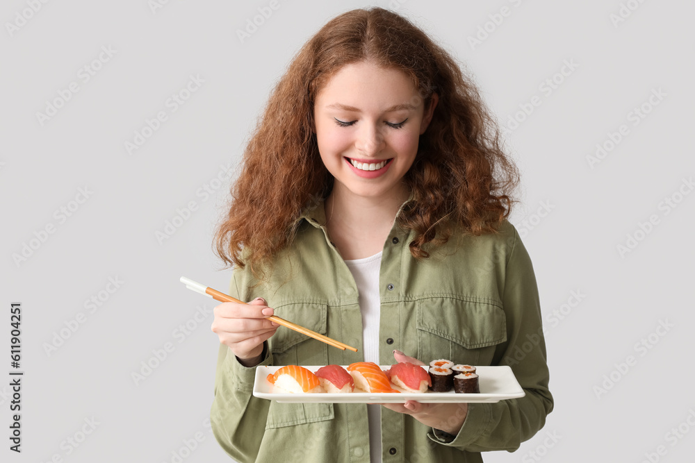 Young woman with sushi on light background