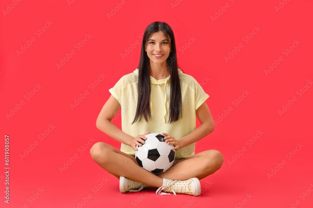 Young woman with soccer ball on red background