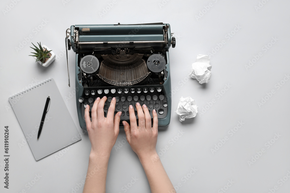 Woman typing on typewriter with notebook, houseplant and crumpled paper on white background