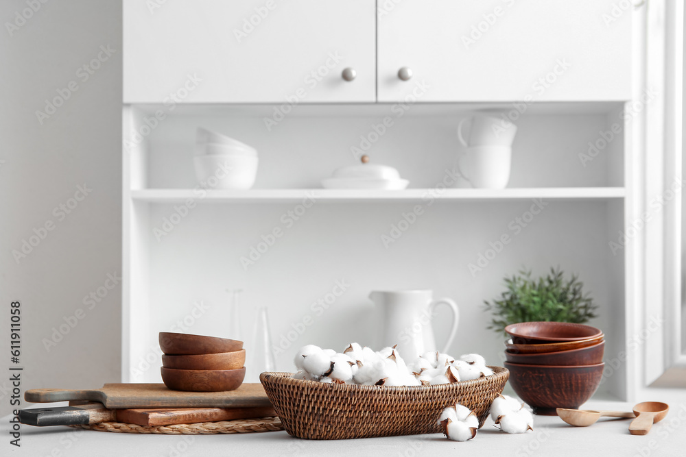 Basket of cotton flowers with kitchen dishes on table