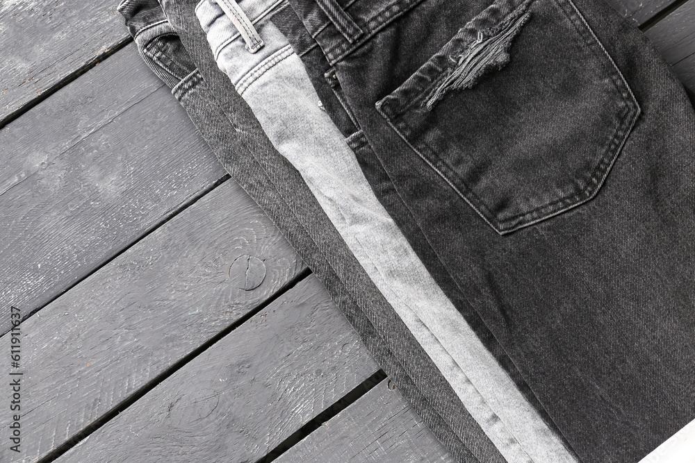 Different stylish denim jeans on grey wooden background