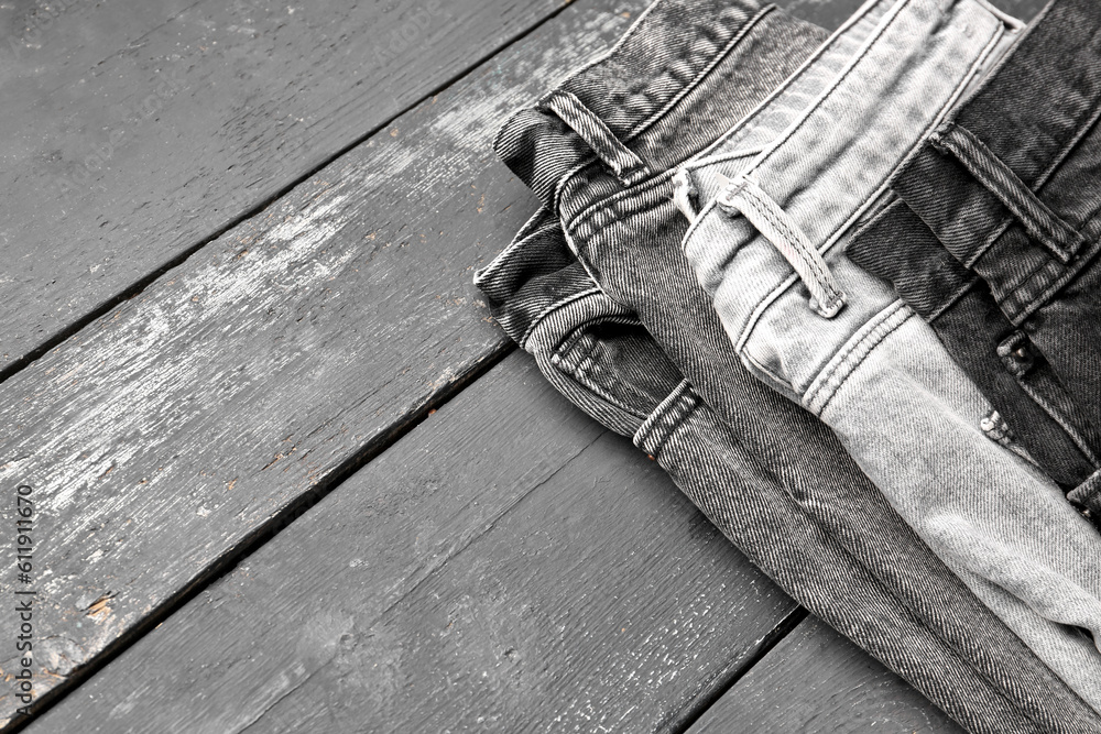 Different stylish denim jeans on grey wooden background