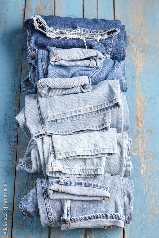 Different rolled jeans on blue wooden background