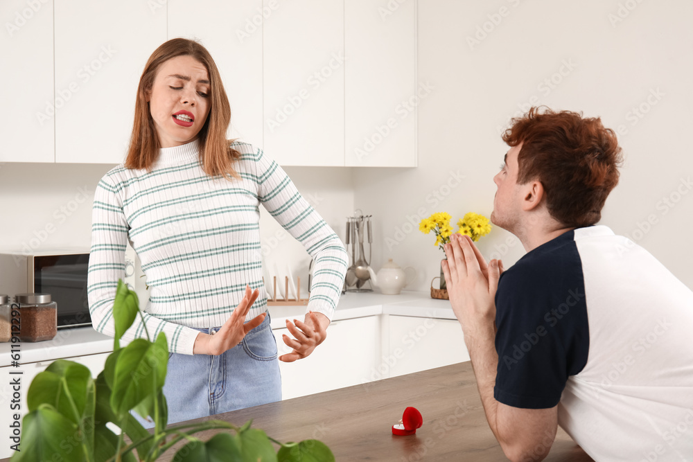 Young woman rejecting marriage proposal in kitchen