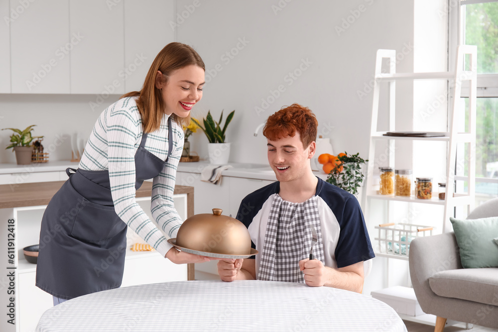 Young woman with cloche proposing to her boyfriend in kitchen