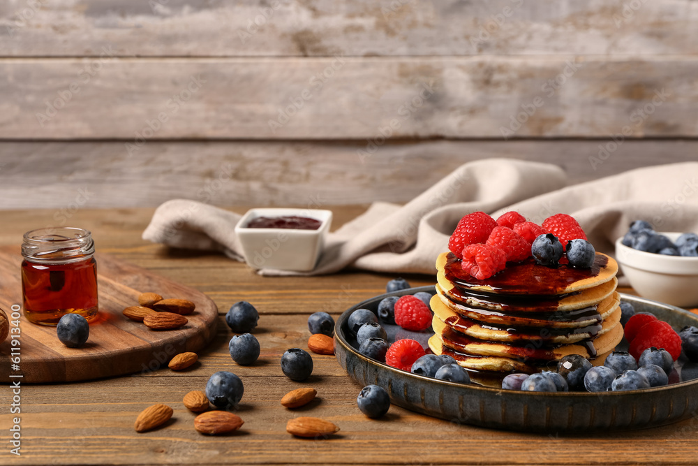 Plate with sweet pancakes, nuts and berries on wooden table