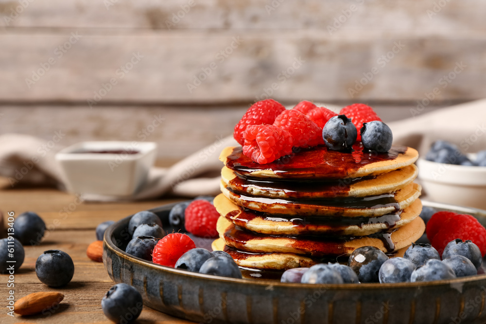 Plate with sweet pancakes, nuts and berries on wooden table, closeup